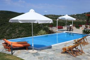 a pool with two chairs and an umbrella at Elies Houses in Agnontas