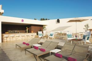 a patio with chairs and tables and a bar at Breathless Cabo San Lucas - Adults Only in Cabo San Lucas