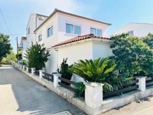 a white house with a fence next to a street at Apartment Schwarz in Petrčane V in Gornje Petrčane