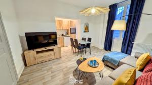 a living room with a couch and a tv and a table at Gite Du Kali in Ensisheim