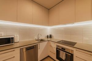 Una cocina con gabinetes blancos, un fregadero y un microondas. en Central 1BR Apt - Balcony Kitchen & Bath, en Christchurch