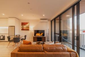 Una sala de estar con un sofá marrón y una mesa. en Central 1BR Apt - Balcony Kitchen & Bath, en Christchurch