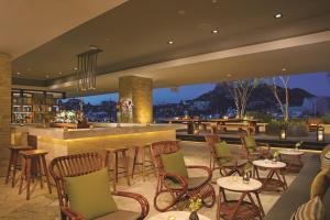 a restaurant with a bar with chairs and tables at Breathless Cabo San Lucas - Adults Only in Cabo San Lucas
