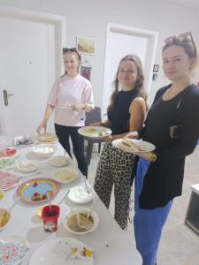 three women standing around a table with plates of food at Downtown Inn Madaba in Madaba