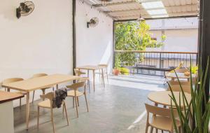 a room with tables and chairs and a large window at Muulao Hostel in Vientiane