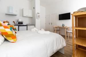 a bedroom with a white bed and a kitchen at Maison Sylvabelle - Confort d'exception - Quartier des Antiquaires - in Marseille