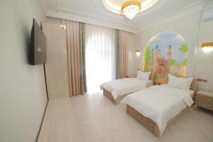a hotel room with two beds and a tv at Turon Khiva in Khiva