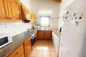 a kitchen with wooden cabinets and a white refrigerator at Villa Mar in Cala en Bosc