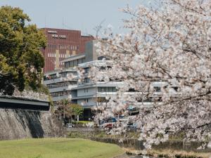 a tree with pink flowers in front of a building at Kumamoto Hotel Castle in Kumamoto