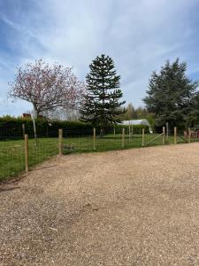 a fence next to a field with a tree at Gullers End Farm Cottage in Long Green