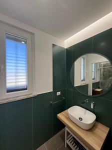 a bathroom with green walls and a sink and a mirror at Villa Rubino - Camere in Palermo +49 photos