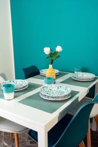 a table with plates and a vase with flowers on it at Colè House in Bitetto