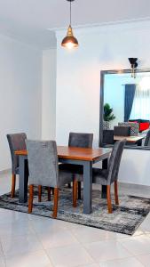 a dining room table with chairs and a mirror at 2 Bedroom Spacious Kampala Buwate Stay A few Steps from the Mall in Buwate