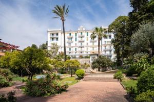 a large white building with a palm tree at Pool and Relax at Casa Ilenia in Bordighera