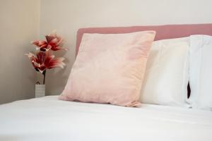 a white bed with a pink pillow and a vase with flowers at Pool and Relax at Casa Ilenia in Bordighera +28 photos