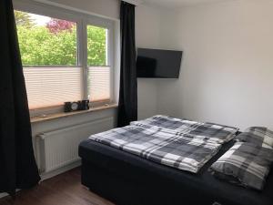 a bedroom with a bed with a plaid blanket and a window at Haus Larum App. 3 in Scharbeutz