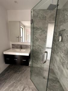a bathroom with a sink and a glass shower at Easy Beach Holiday in Mount Maunganui +18 photos