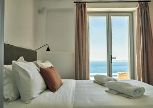 a bedroom with a bed with pillows and a window at Hotiday Mykonos Fanari in Mikonos