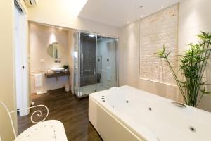 a bathroom with a large white tub and a shower at Trullo Melograno - Luxury & Spa in Alberobello
