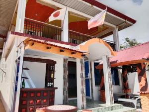 a house with a red door and a balcony at WJV Inn Beach Resort Camotes in Camotes Islands