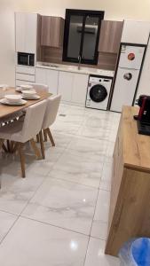 a kitchen with a table and a white tile floor at Hotel Apartment - 4 - LAvner Al hussma in Quai