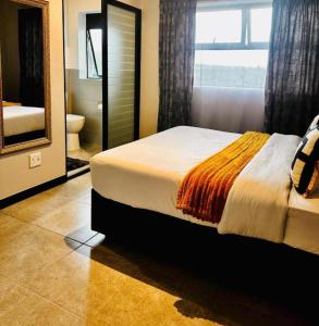 a bedroom with a bed and a large mirror at StayEase Modern Stay in Waterfall in Midrand