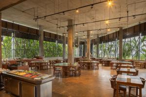 Un restaurante con mesas y sillas y grandes ventanales. en Sunday Sea Two Pool Villa Pattaya, en Jomtien Beach