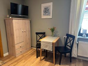 a dining room with a table and chairs and a television at HeideZeit Appartment in Neuenkirchen