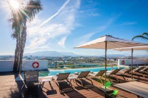 a deck with chairs and umbrellas and a pool at Hotel Málaga Vibes in Málaga