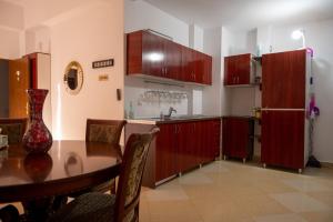 a kitchen with red cabinets and a table and a refrigerator at Vila Nicoleta in Băile Olăneşti
