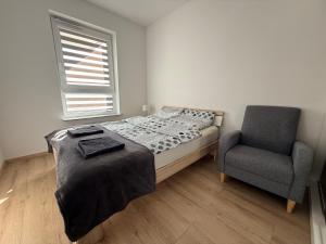 a bedroom with a bed and a chair at Apartament Mike - free parking self check-in in Giżycko