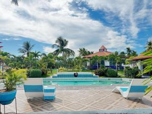 a resort swimming pool with chairs and palm trees at Galaxy Family Room in Dalaguete