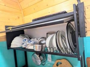 a shelf with plates and utensils on it at Hồ Mây Homestay in Bảo Lâm