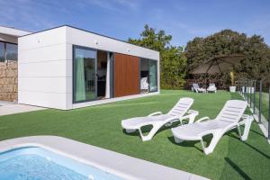 una casa con un prato con sedie e una piscina di Bungalow 2 con piscina en la playa a A Pobra do Caramiñal