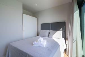 una camera da letto con un letto e un asciugamano sopra di Bungalow 2 con piscina en la playa a A Pobra do Caramiñal Altre 15 foto
