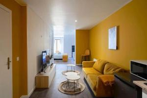 Sala de estar amarilla con sofá y mesa en NG Prestige - Suite Soleil Doré - Balnéo - Cuisine - Jardin, en Roubaix