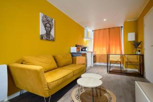 Una sala de estar con un sofá amarillo y una mesa. en NG Prestige - Suite Soleil Doré - Balnéo - Cuisine - Jardin, en Roubaix