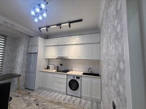 a kitchen with white cabinets and a dishwasher at Amanat residence in Osh +4 photos