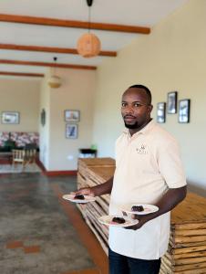 a man holding two plates of chocolate desserts at Mvuli Mountain Lodge Ngorongoro in Karatu