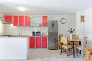 a kitchen with red cabinets and a table with chairs at Apartment Ana-Rapavel in Višnjan +5 photos