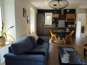 a living room with a blue couch and a kitchen at Maison de Kerangall Brest appartement jardin et parking in Brest