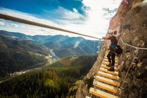 a man on a rope bridge on a mountain at Red Lake Apartman in Lacu Rosu
