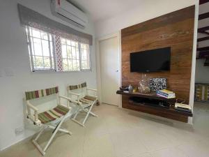a living room with two chairs and a flat screen tv at Casa de Condomínio em Maresias próximo a praia! in São Sebastião