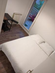 un letto bianco in una stanza con una finestra di Capbreton 2 bedroom apartment between forest and beach a Capbreton