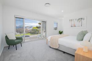 a bedroom with a bed and a chair and a window at Shoreline Luxe - Refined Beachside Elegance with Spa in Caves Beach