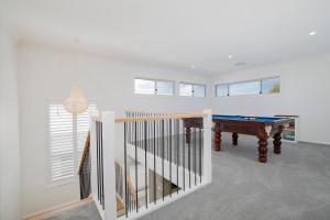 a room with a pool table and a staircase at Shoreline Luxe - Refined Beachside Elegance with Spa in Caves Beach