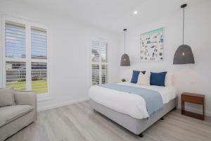 a white bedroom with a bed and a couch at Shoreline Luxe - Refined Beachside Elegance with Spa in Caves Beach