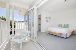 a bedroom with a bed and a chair on a balcony at Shoreline Luxe - Refined Beachside Elegance with Spa in Caves Beach