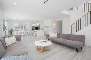 a living room with a couch and a table at Shoreline Luxe - Refined Beachside Elegance with Spa in Caves Beach