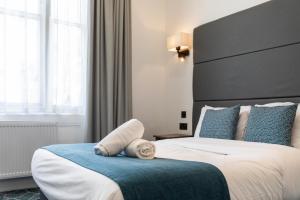 a bedroom with a large bed with a large headboard at The J Hyde Park Hotel in London